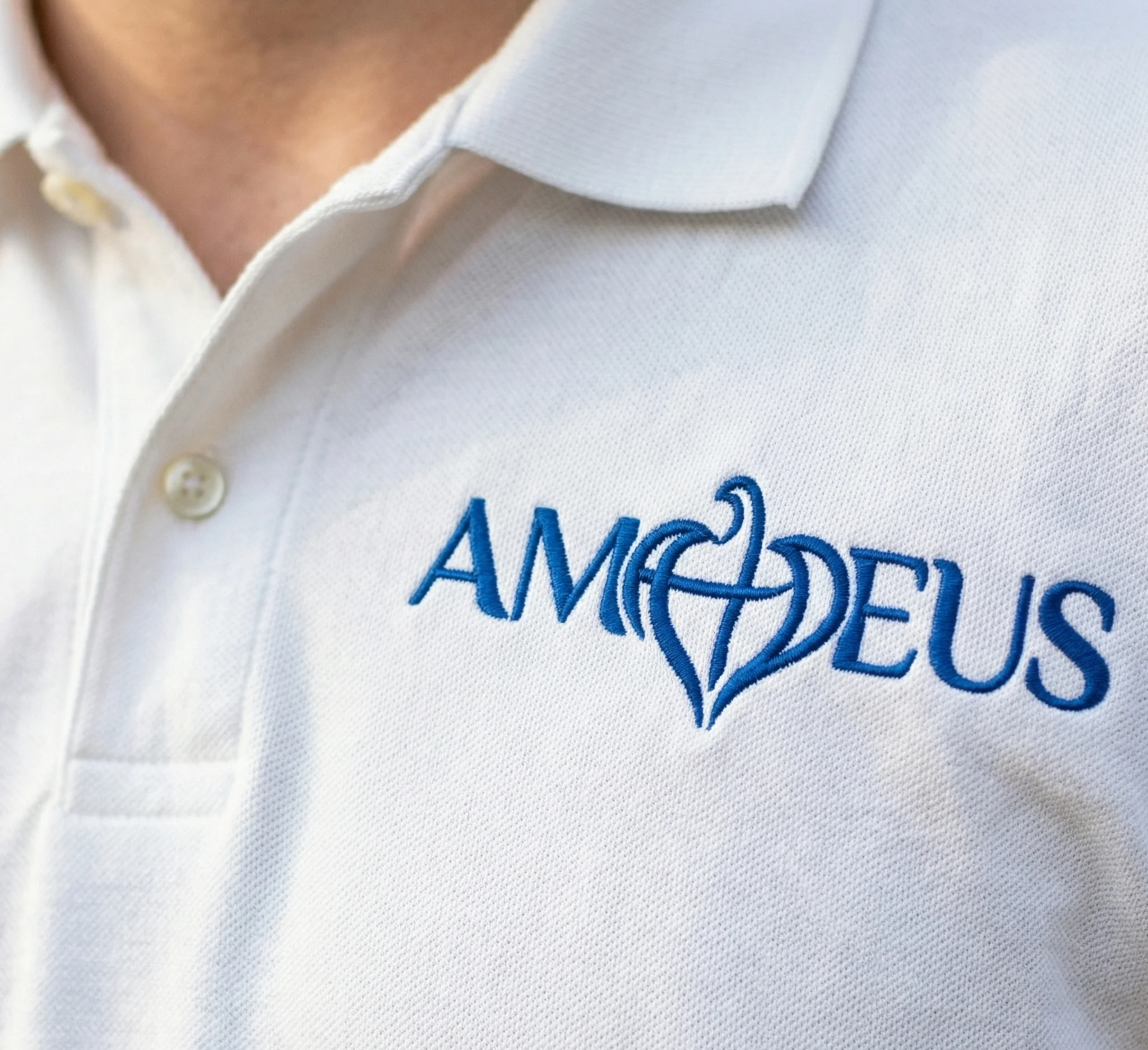 Logotip Amadeus izvezen plavim koncem na bijeloj polo majici